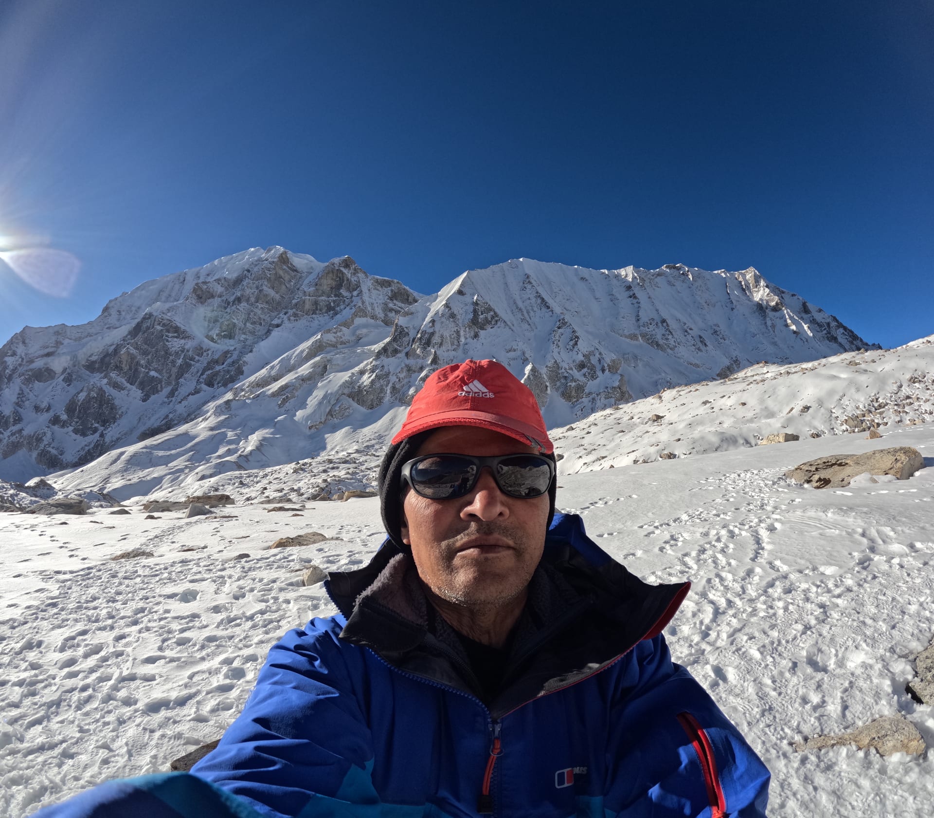 Mount Manaslu (8,163 m) viewed from the Samagaon side of the Manaslu Circuit Trek, with prayer flags in the foreground and the Larkya Himal range stretching toward the Larke La pass.